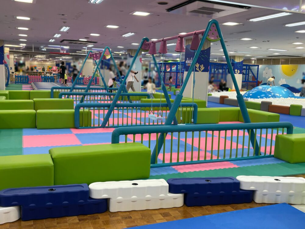 幼児〜小学校低学年向けのブランコエリア。やわらかいマットの上に設置された安全設計で、1人ずつ順番に遊べる遊具