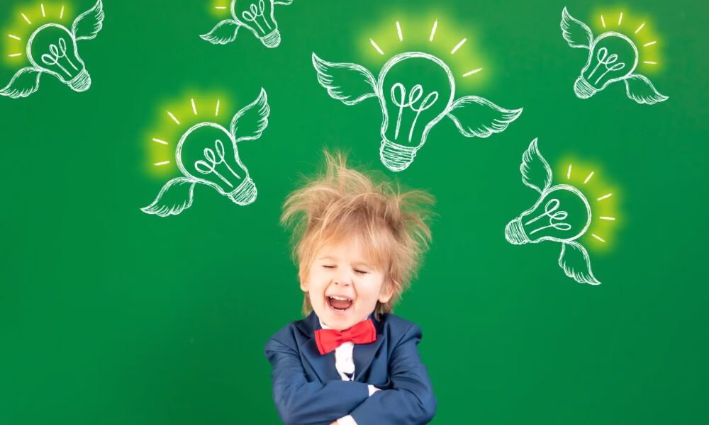 男の子がアイディアをひらめく様子。背景はグリーンで数個の電球に羽が付いている。
