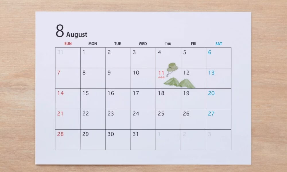 木の机に白の8月のカレンダーが置いてある