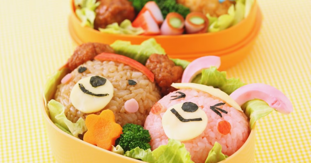 運動会のお弁当。うさぎとくまのおにぎりが入ってる。周りにはレタスと人参、ブロッコリーが敷き詰められている。