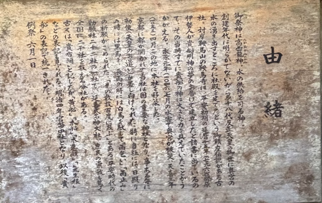 貴船神社 本宮に祀られる高龗神（たかおかみのかみ）の由緒を紹介する木製の案内板。水と雨を司る神として古くから信仰されていることが書かれている。