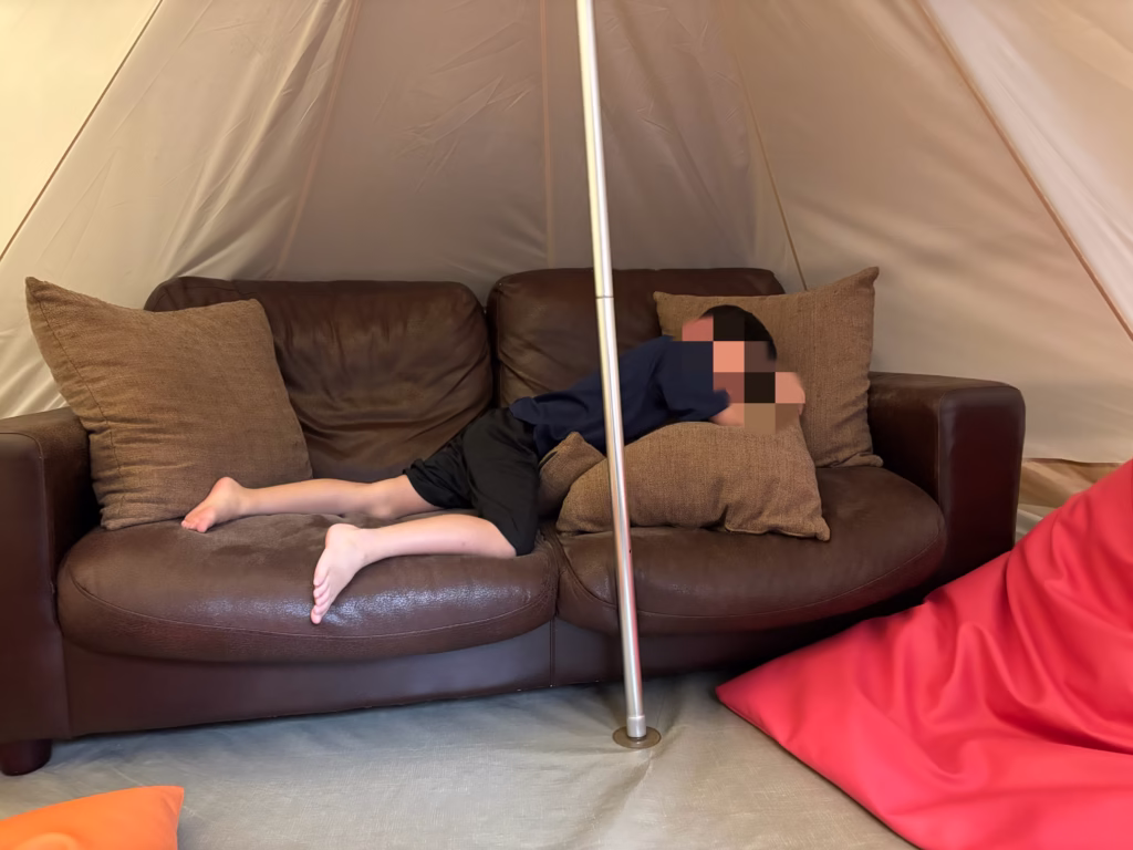 るり渓温泉のランタンテラスにあるテントで横になる子ども